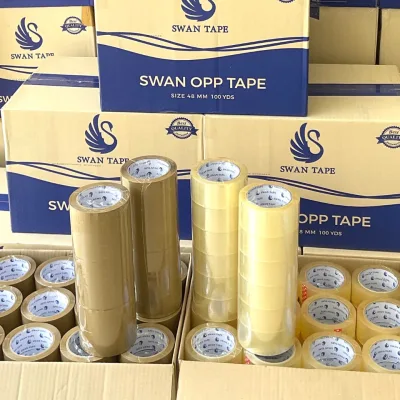 กล่อง SWAN OPP TAPE ซ้อนสูงในคลัง ด้านหน้าเป็นม้วนเทปใสและน้ำตาลตั้งเรียง — SWAN TAPE โรงงานผลิตเทปกาว