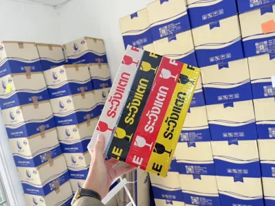 มือถือปึกเทประวังแตกหน้ากองลังสินค้าที่เรียงสูงเต็มคลัง — SWAN TAPE โรงงานผลิตเทปกาว