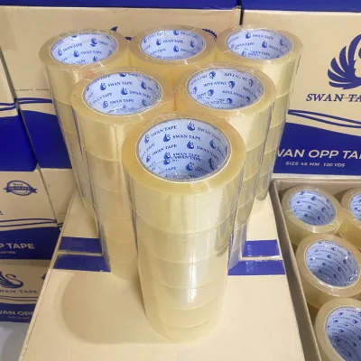 ม้วนเทปใสตราสวอนตั้งเรียงแน่นอยู่ในกล่องที่เปิดฝารอแพ็ก — SWAN TAPE โรงงานผลิตเทปกาว