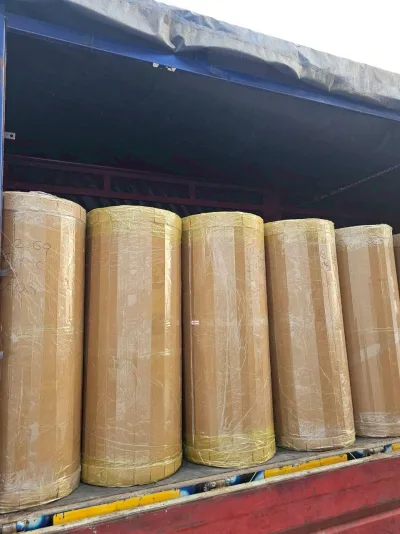 ม้วนจัมโบ้ห่อฟิล์มเหลืองเรียงเต็มกระบะรถบรรทุกที่คลุมผ้าใบ — SWAN TAPE โรงงานผลิตเทปกาว