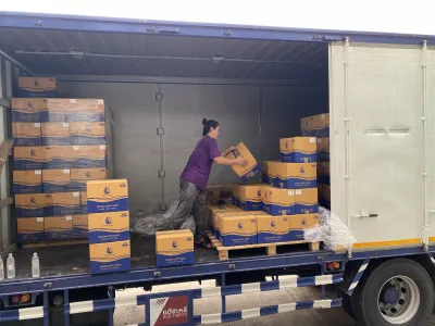 พนักงานยกกล่องเทปเดินจัดของอยู่ท้ายตู้รถบรรทุกที่เปิดอยู่ — SWAN TAPE โรงงานผลิตเทปกาว