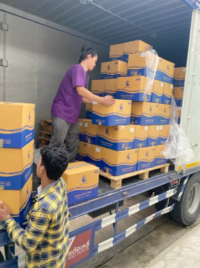 พนักงานสองคนช่วยกันส่งกล่องเทปขึ้นตู้รถบรรทุกที่จอดเทียบอยู่ — SWAN TAPE โรงงานผลิตเทปกาว