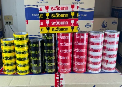 ม้วนเทประวังแตกสี่สีเรียงเป็นแถวหน้ากองลังสินค้าในคลัง — SWAN TAPE โรงงานผลิตเทปกาว